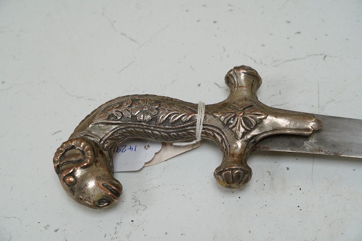 A decorative Indian sword, Shamshir hilt of embossed silver plated copper with a rams head pommel, blade 73.5cm. Condition - good